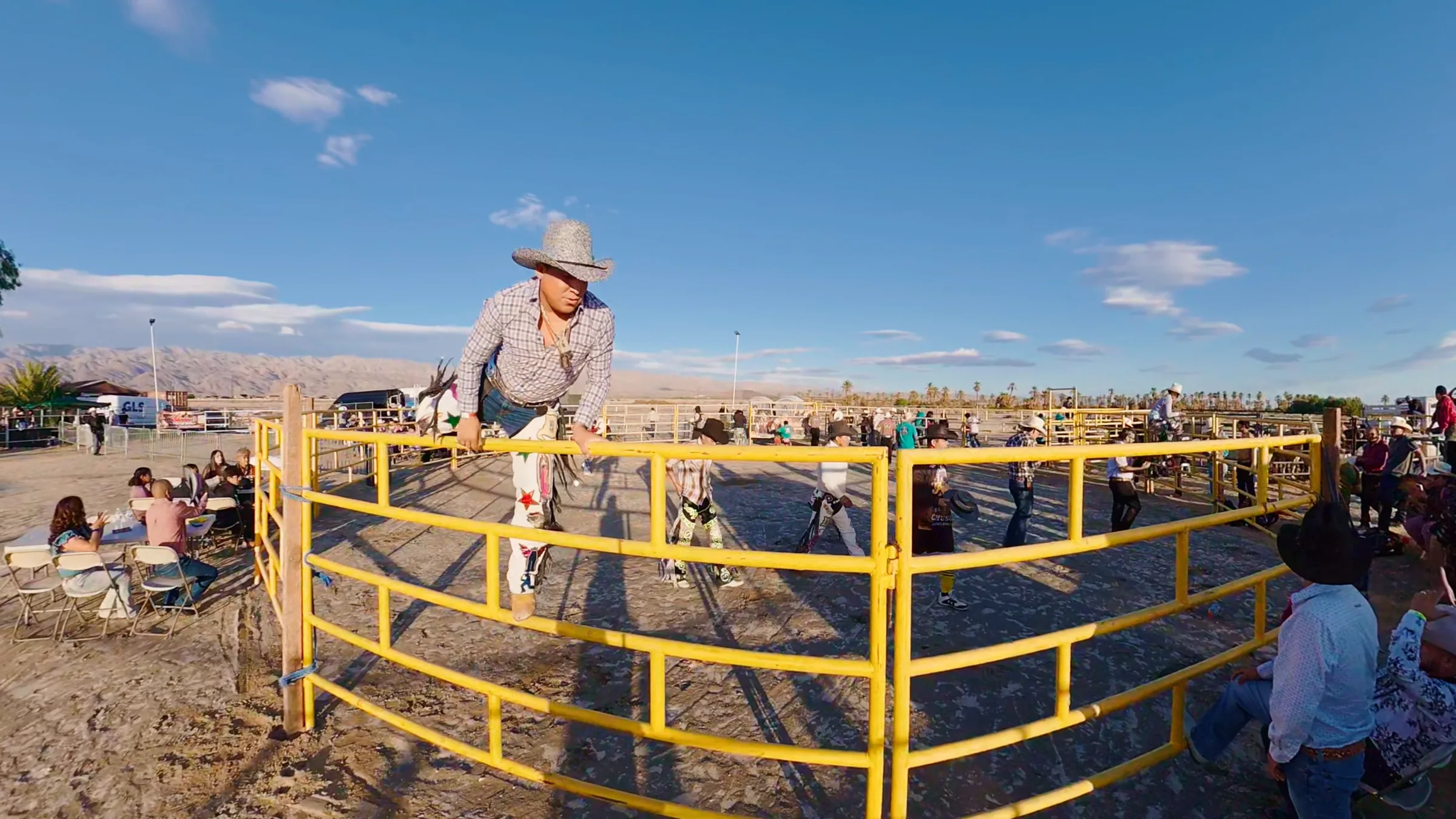 A rider moving over the yellow arena gate during the jaripeo
